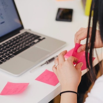 Girl working with sticky notes and laptop