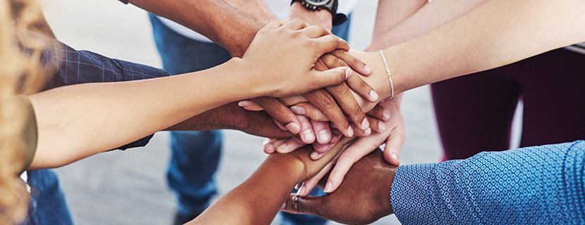 group of people in a circle putting their hands together