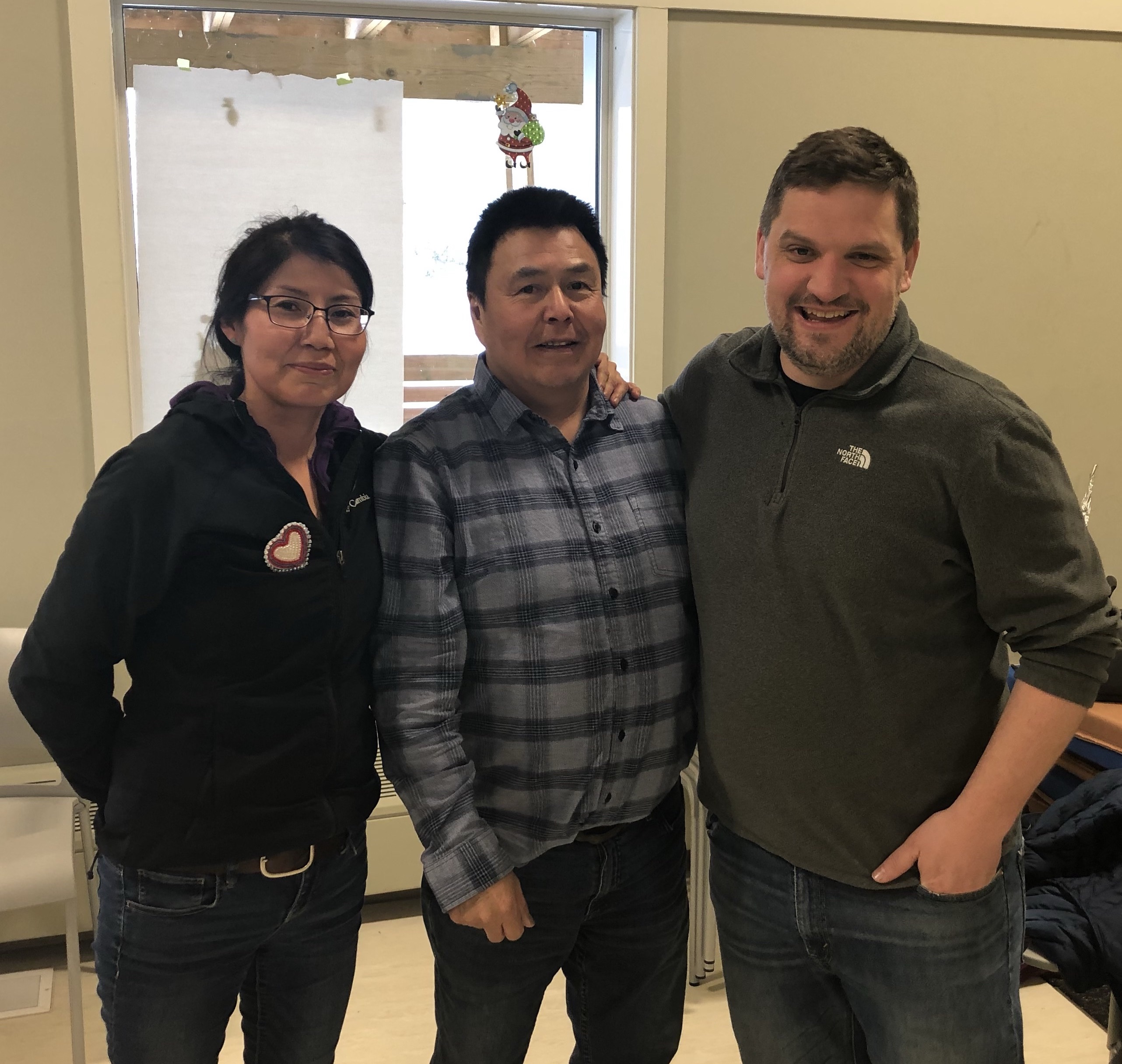 Community research partners Melaine Simba and Chief Lloyd Chicot with researcher Andrew Spring posing for a photo inside of a bright room
