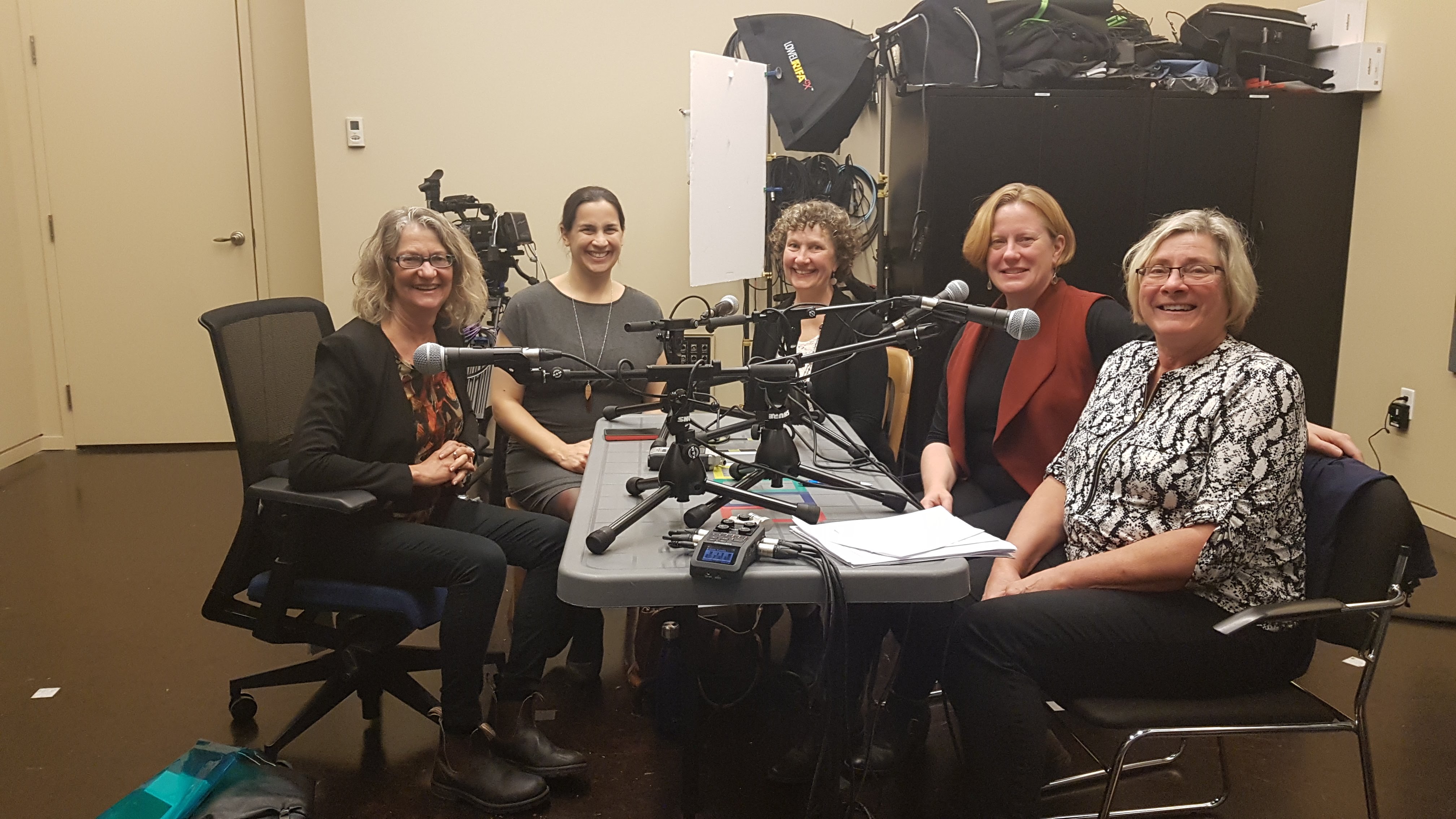 five women seated around a table with audio recording equipment