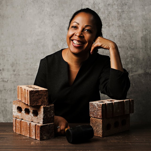 a woman sits at a table with bricks