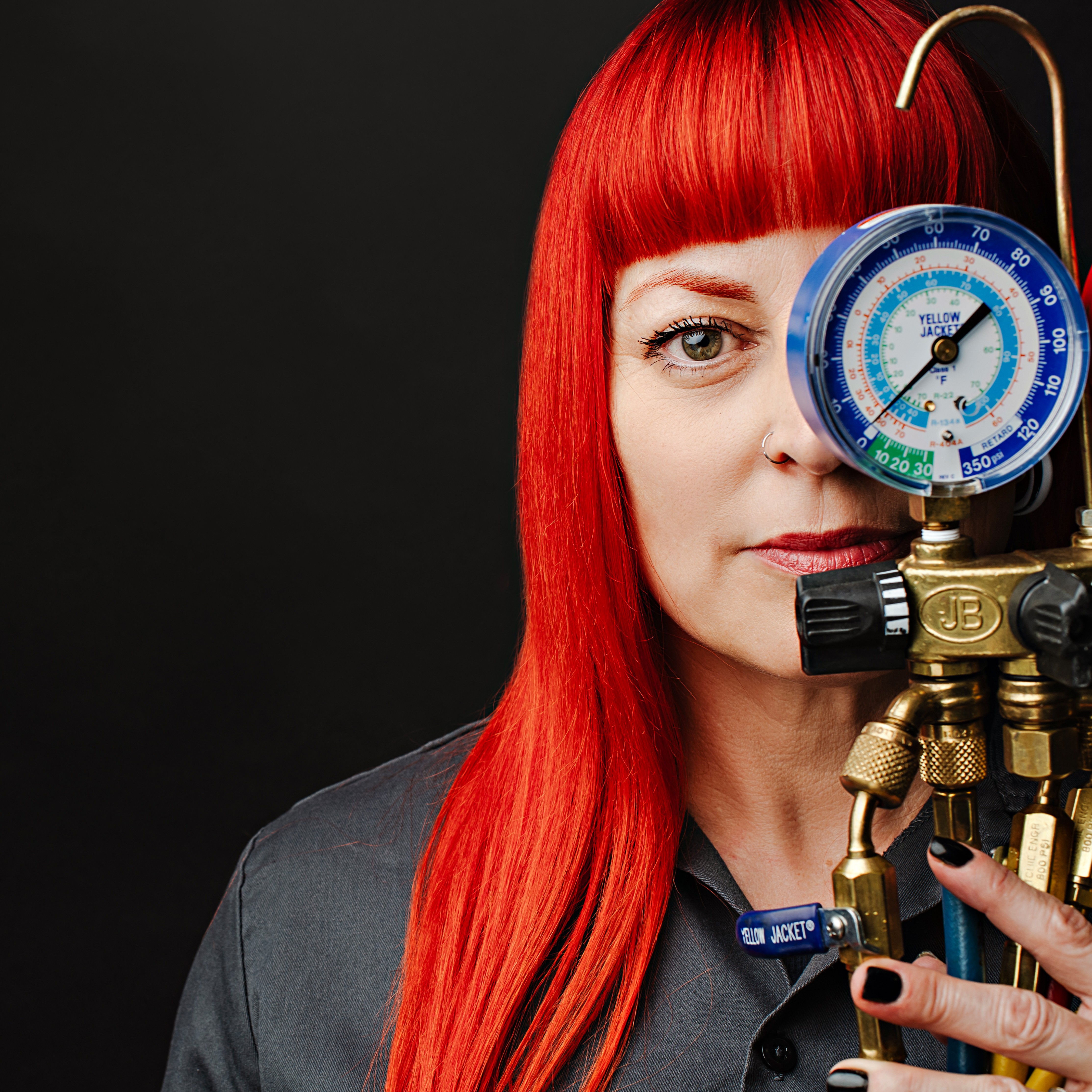 a woman with red hair looks through a gauge