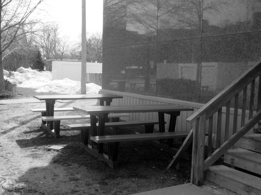 two empty picnic bench tables beside building