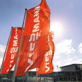 Spotlight story image pertaining to viessmann building with 3 company flags flowing sunshine bursting through